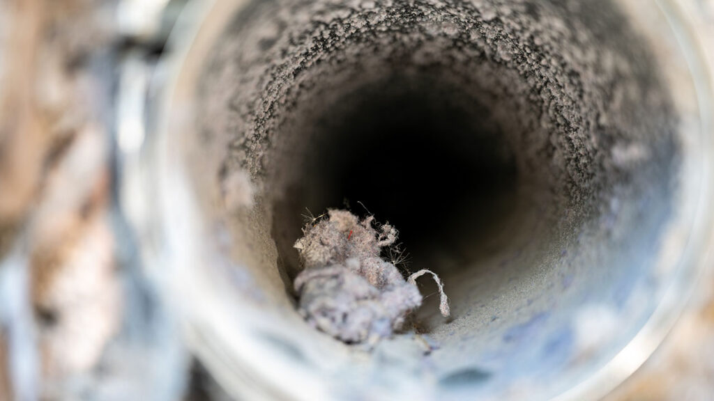 Interior view of dryer vent line with lint and dust buildup