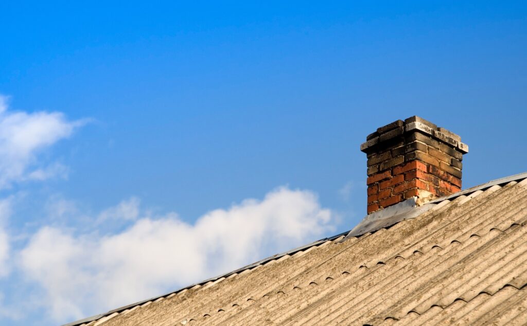 Old chimney with a view of a roof and a view of the sky in the background.