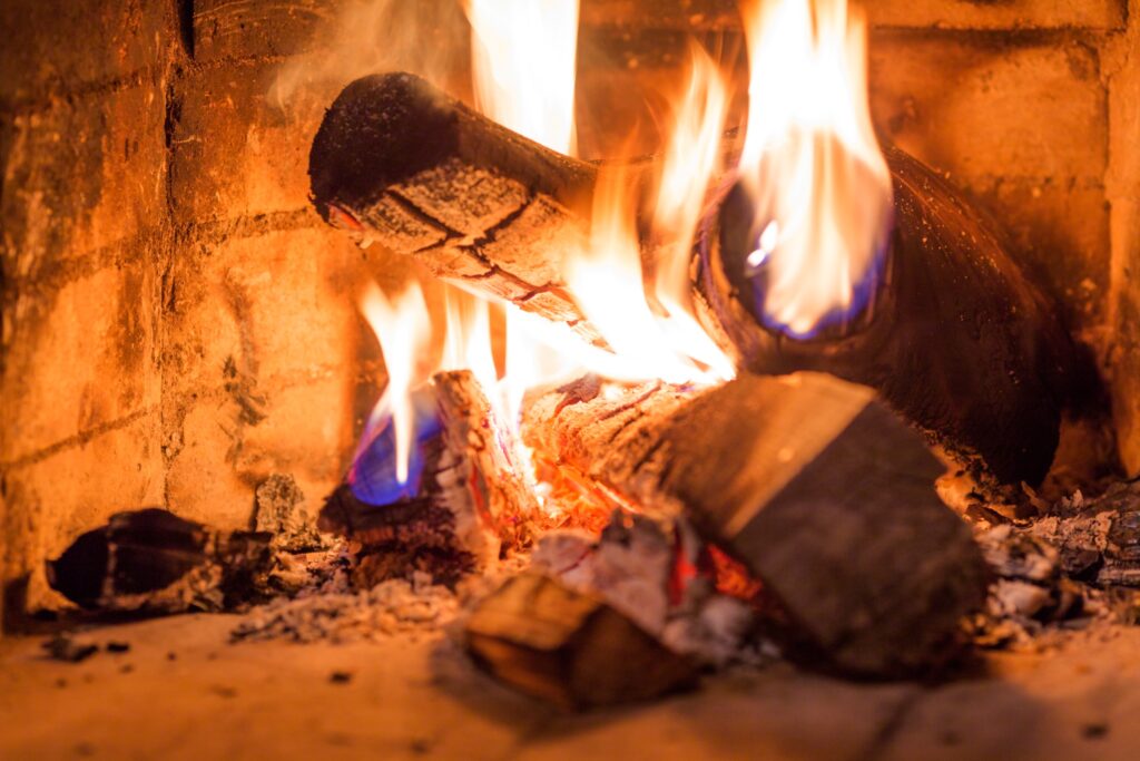 Logs on fire inside of a stone fireplace.